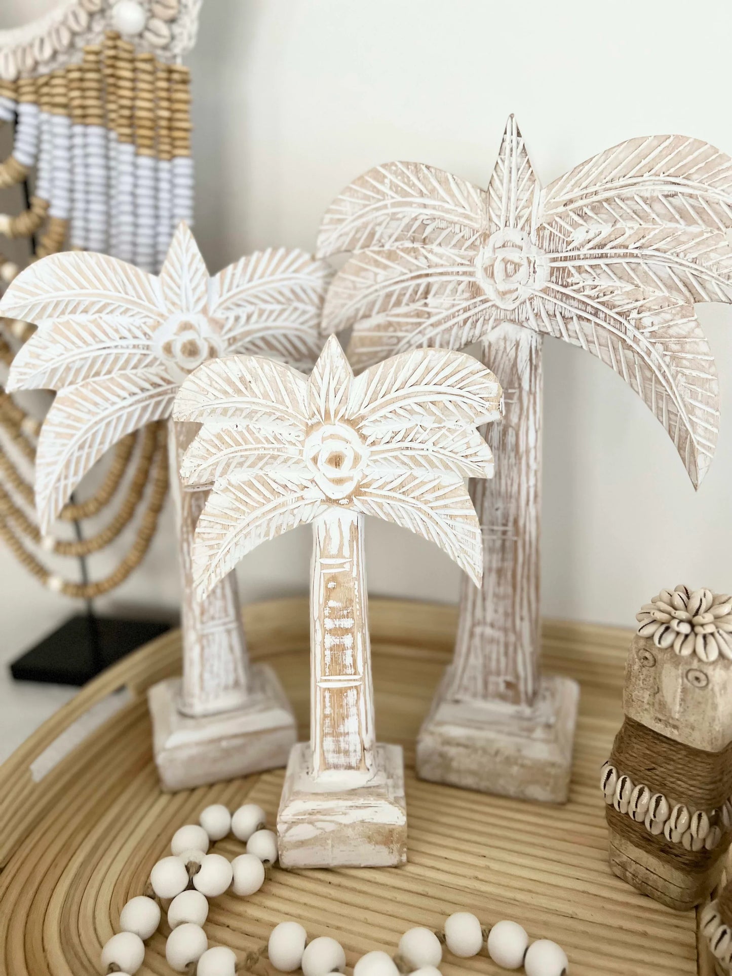 Decorative palm tree sculptures on a wooden surface with beads.