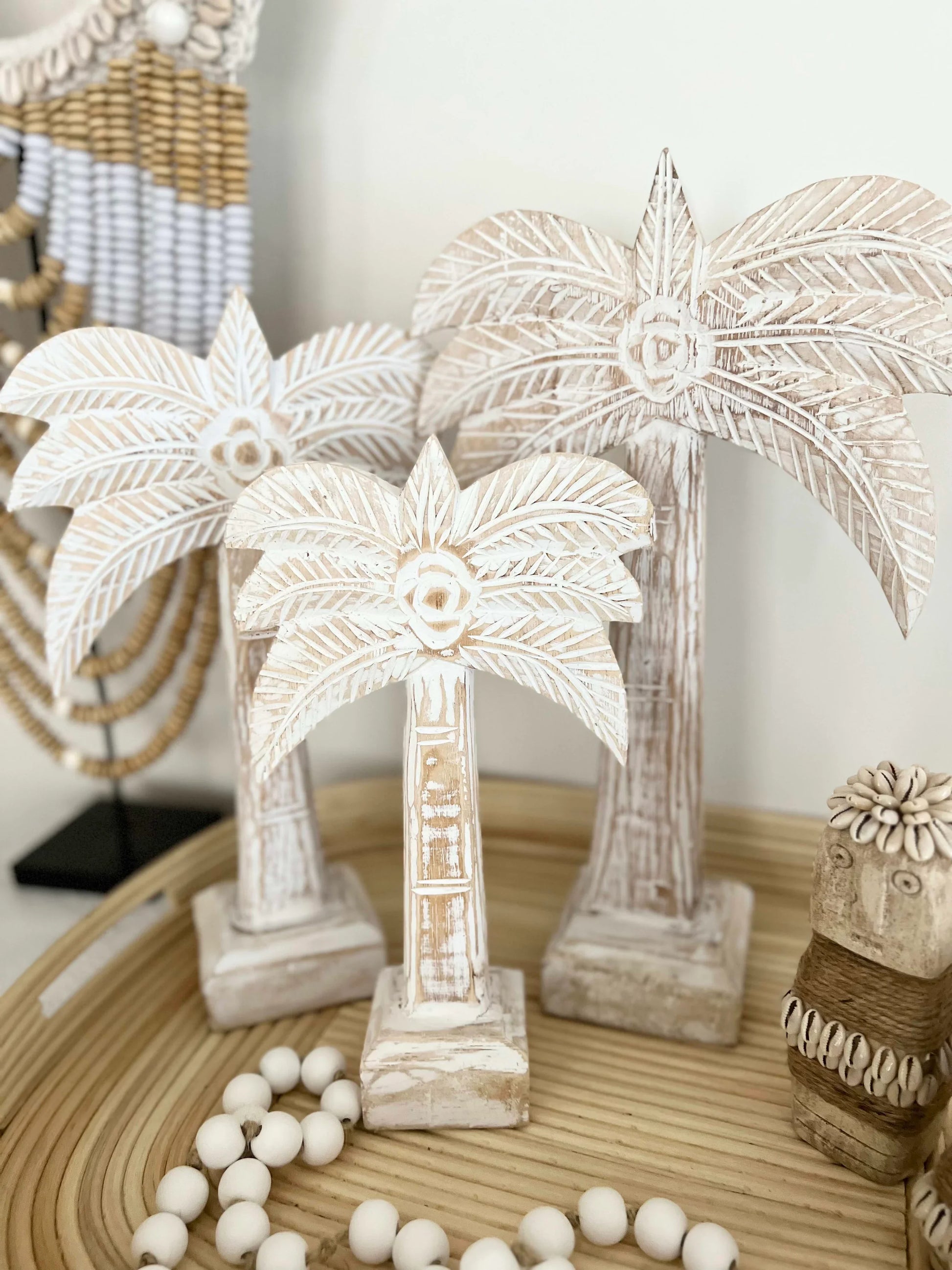 Decorative palm tree sculptures on a wooden surface with beads.