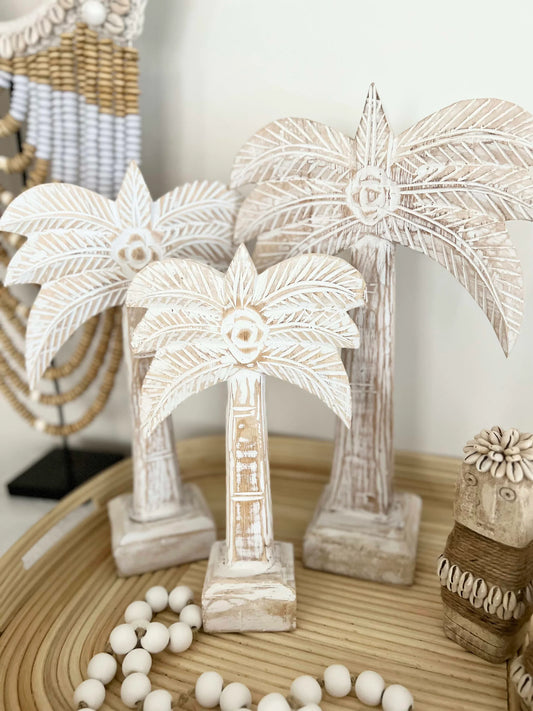 Decorative palm tree sculptures on a wooden surface with beads.